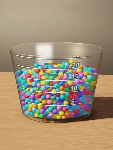 A glass bucket filling with colorful marbles